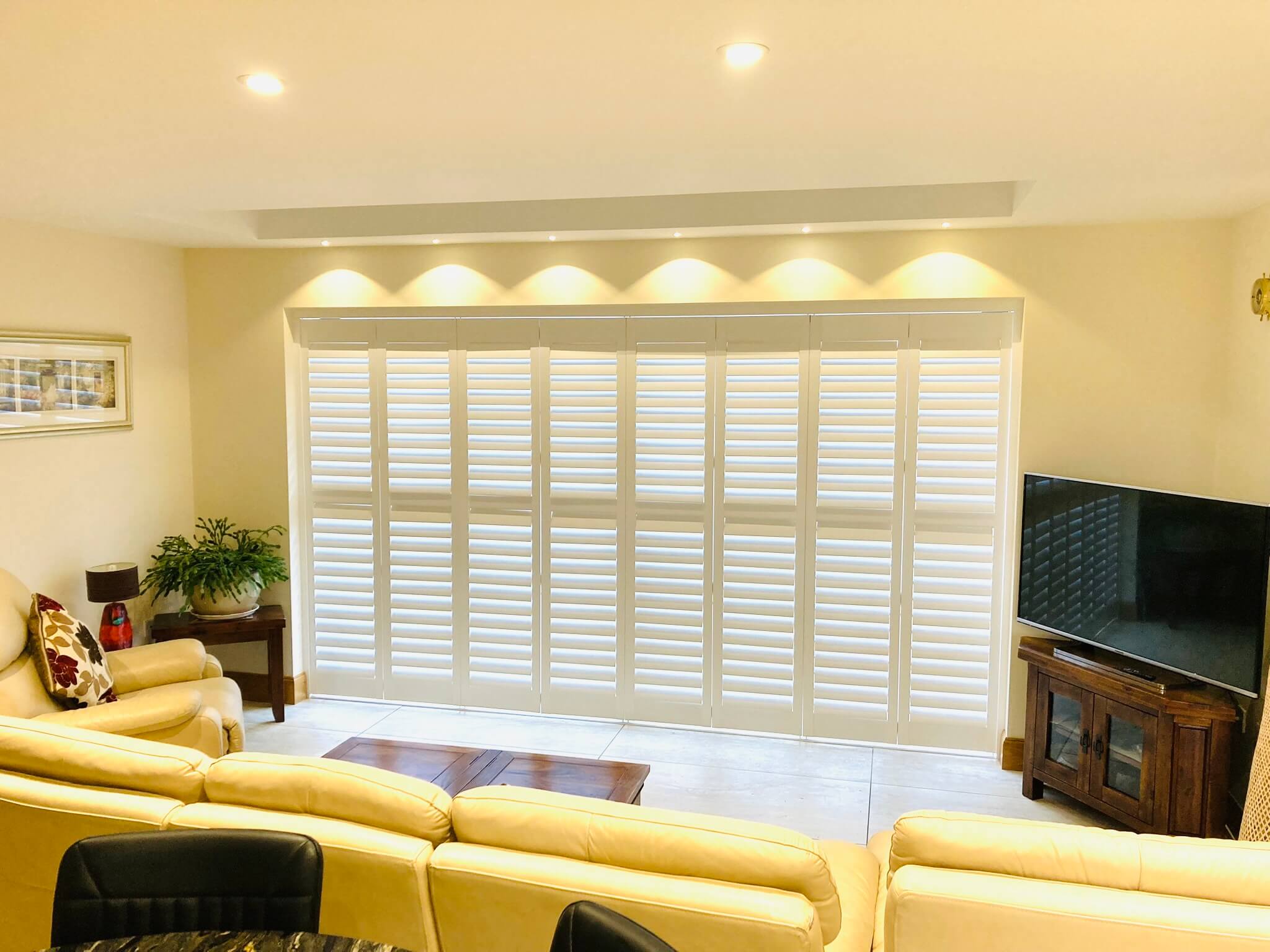 Tracked bifold shutters spanning a large living room opening